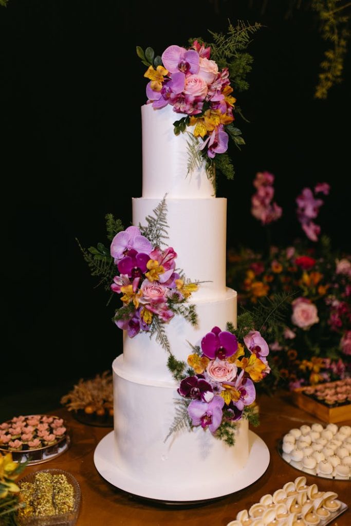 A beautifully decorated four-tier wedding cake adorned with vibrant flowers, perfect for elegant celebrations.